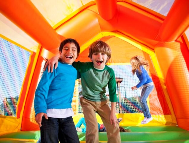 Two boys laughing inside an Elite Event Rentals bounce house