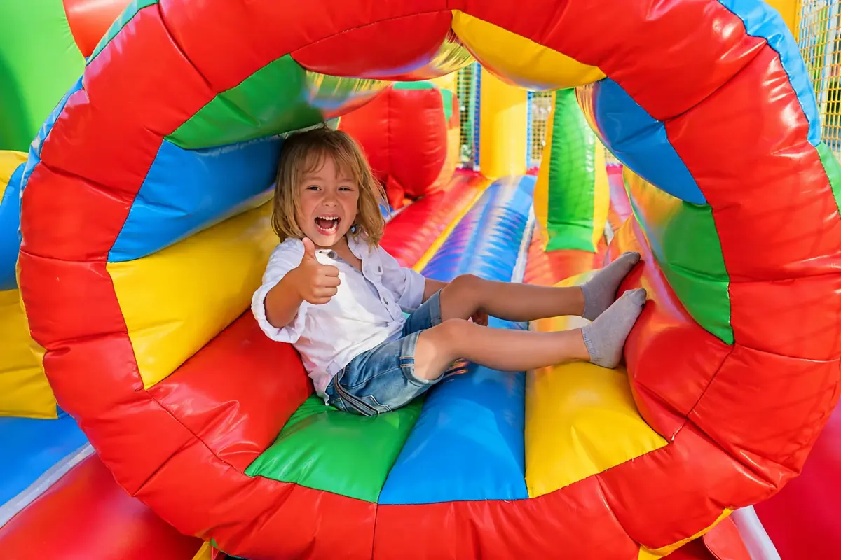 Child giving a thumbs-up inside a Jump N Bounce inflatable obstacle course