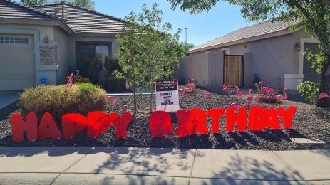 big red Happy Birthday letters and flamingos  in yard