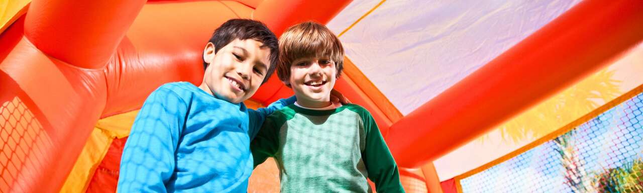 Kids playing on inflatable bounce house and water slide at backyard party