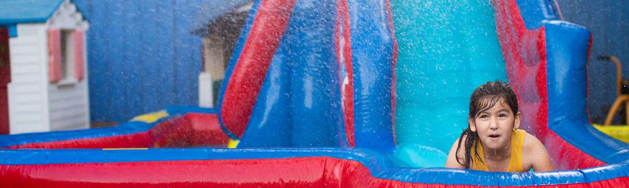 Kids enjoying double-lane water slide at end of school party