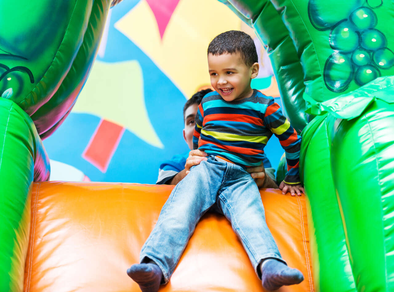 Young boy at the top of an inflatable castle slide from Busy Bee Jumpers in Rhode Island Young boy at the top of an inflatable castle slide from Busy Bee Jumpers in Rhode Island