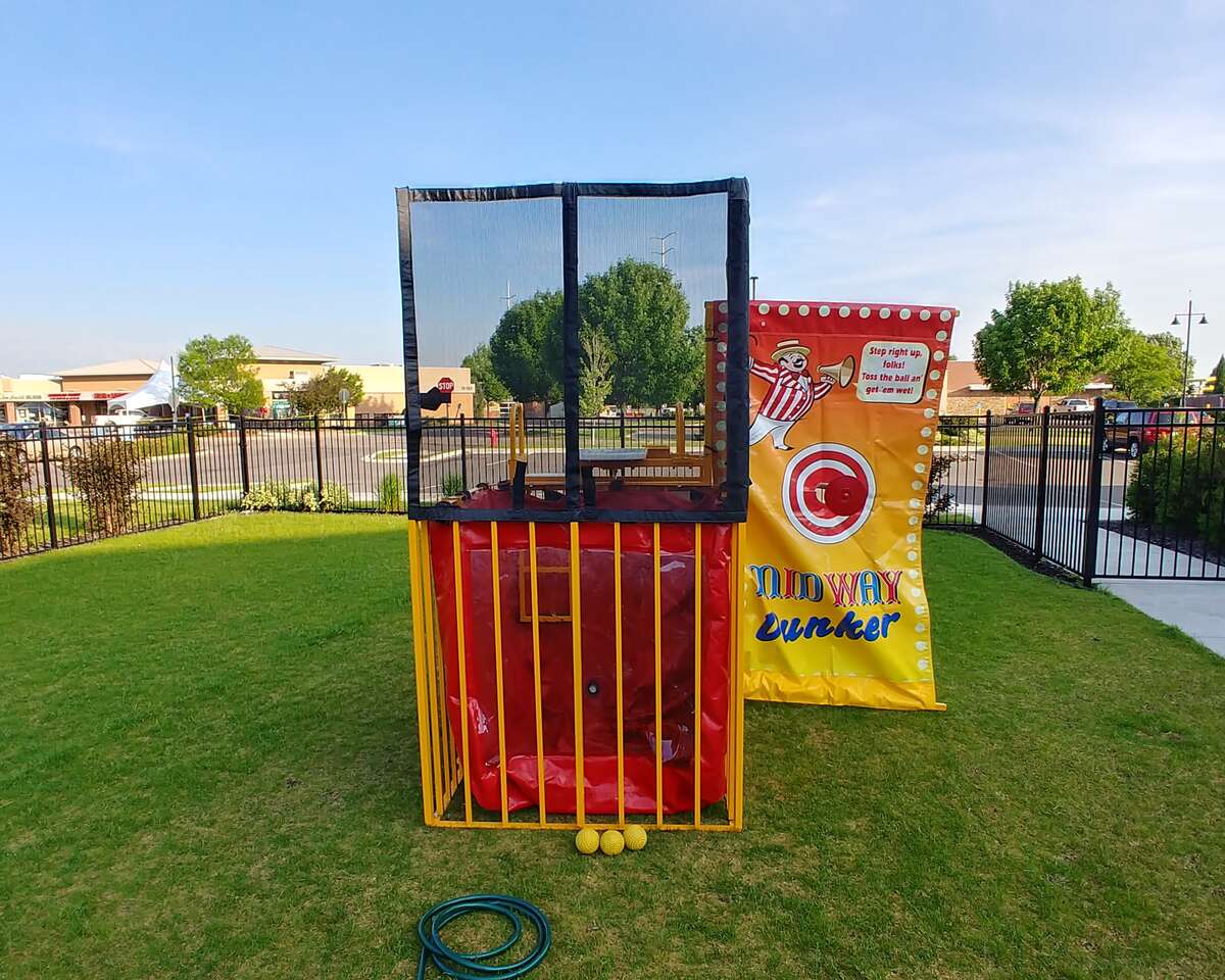 Carnival dunk tank game setup on a grassy field with target board, water tank, and throwing balls for outdoor events and parties.