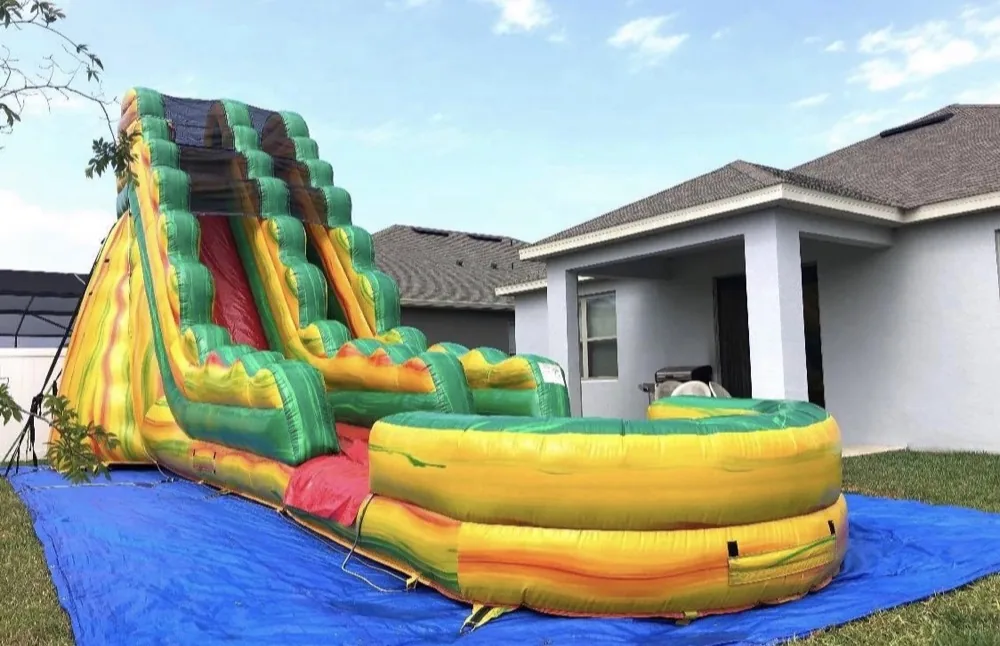 Green and yellow tropical inflatable water slide with a splash pool
