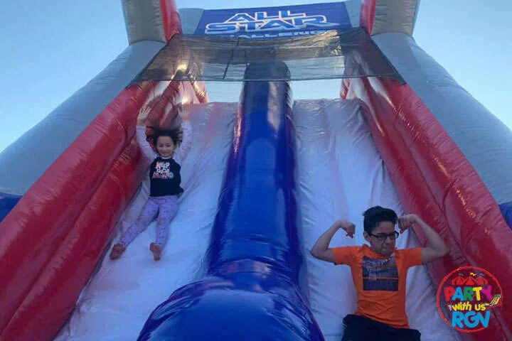 Children sliding down a red and blue inflatable water slide