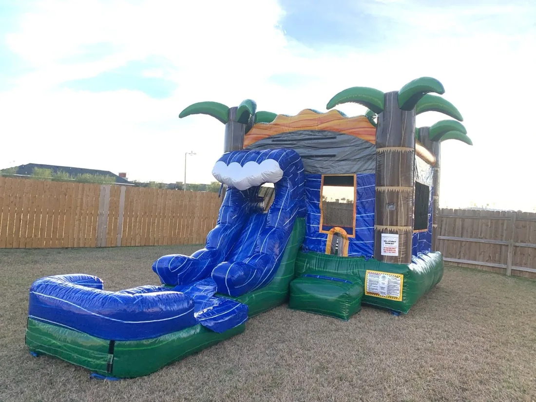 Blue tropical inflatable water slide with palm-tree decorations and a splash pool