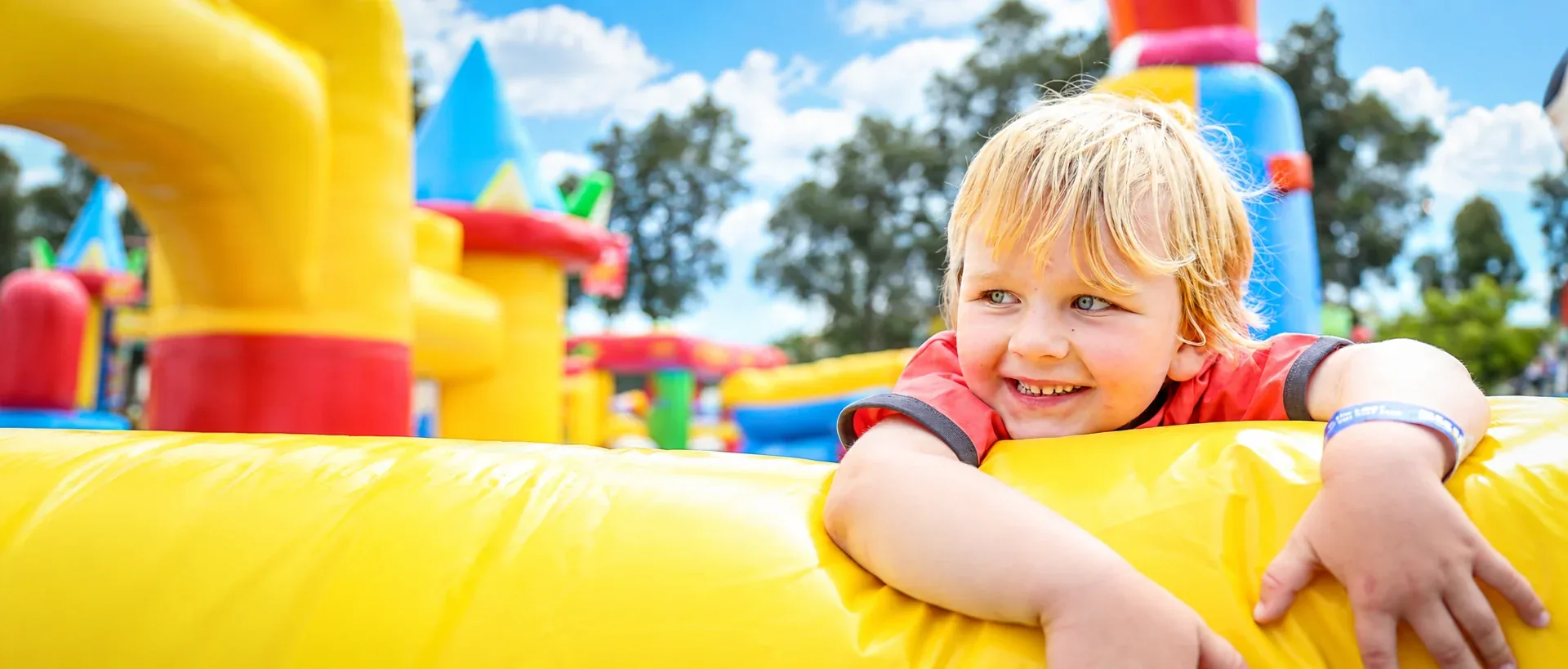 Smiling child enjoying a colorful inflatable attraction at a Party With Us RGV event