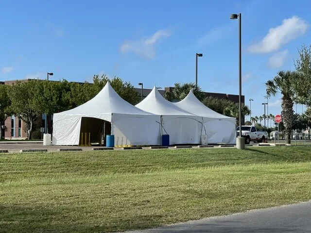 White peaked pole tents set up on a lawn