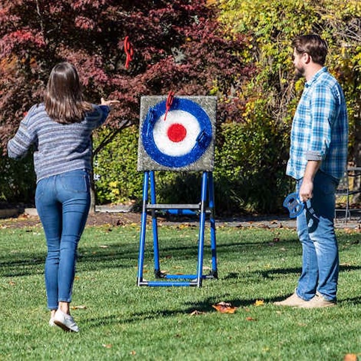Man and woman enjoying Gator Jump's portable axe throwing game at an outdoor event.