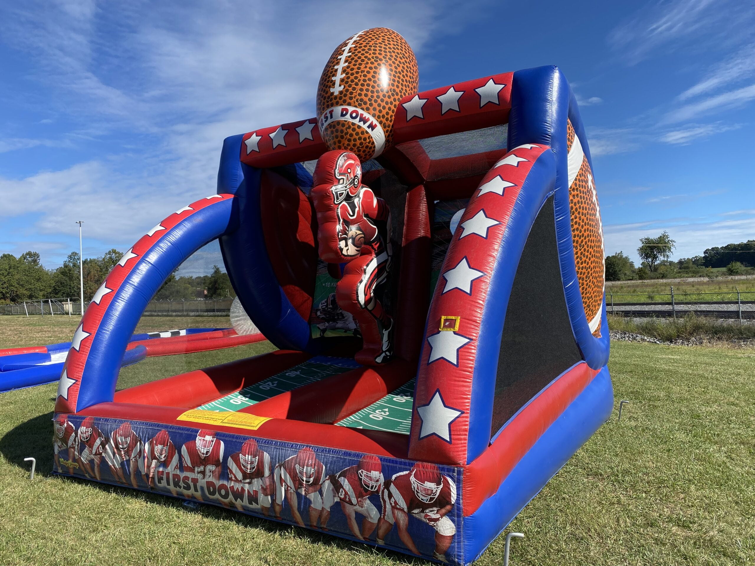 Inflatable football-themed game rental at an outdoor event, with a large football on top.