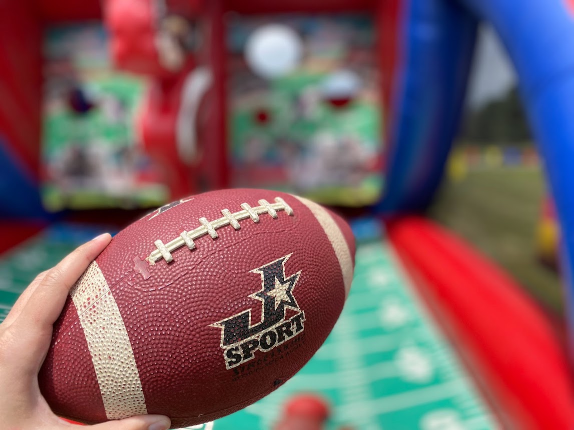 Close-up of a hand holding a football ready to throw in an inflatable game setting.