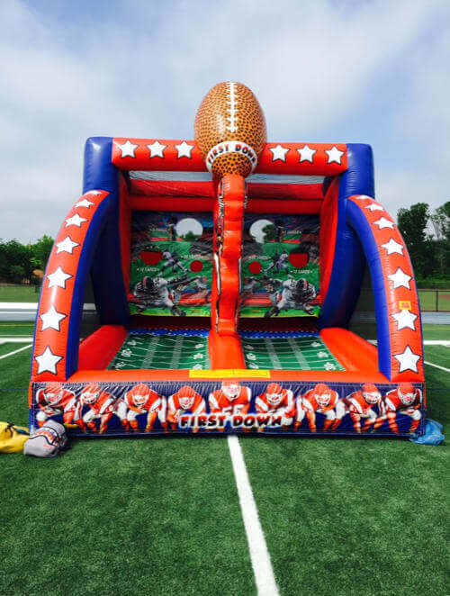 Inflatable football-themed game at an outdoor event, with a large football on top.