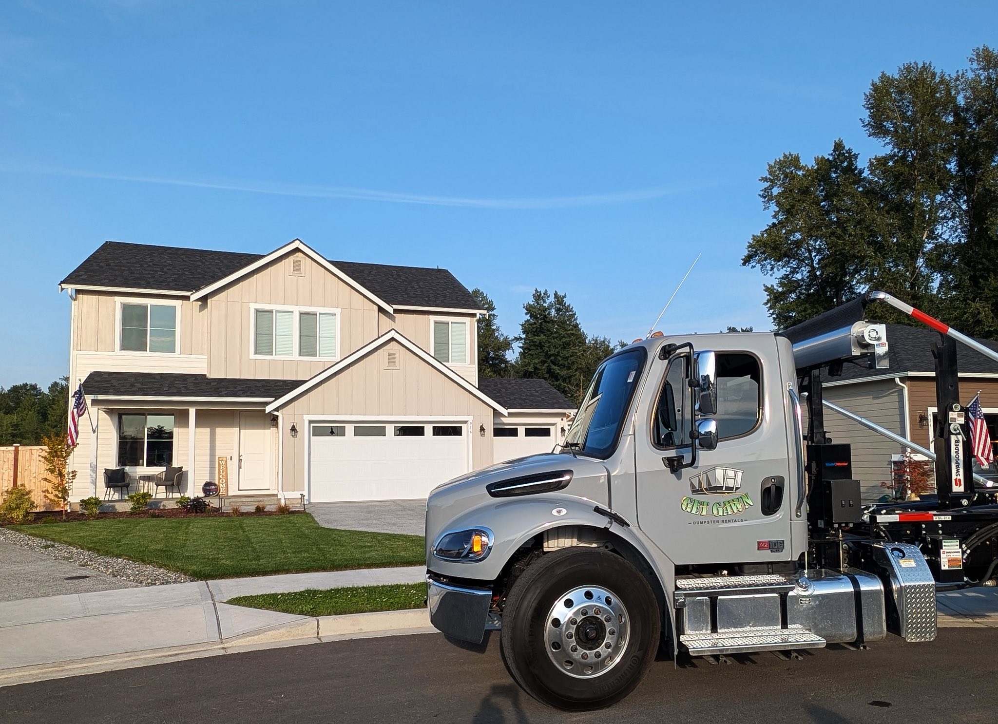 Get Gawn Dumpster Rentals gray truck parked in front of a modern beige suburban home on a clear day