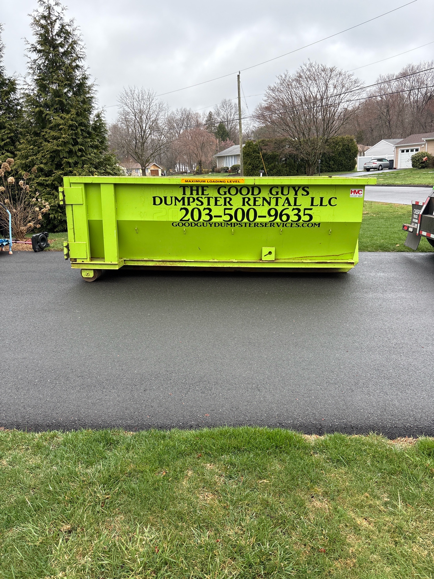 green dumpster container in front of a house