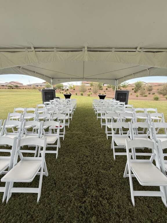 Complete corporate party rental setup with high peak tent resin chairs speakers stage podium tables and commercial coolers in Goodyear Arizona