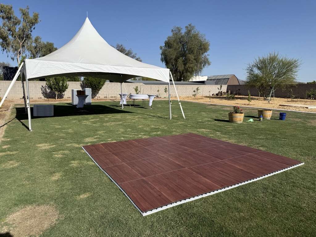 Outdoor wedding dance floor installed on grass near a high peak tent in Goodyear Arizona