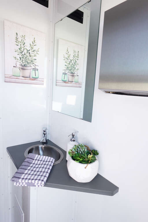 Modern bathroom trailer vanity with running-water sink, mirror and décor