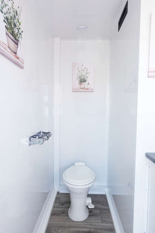 Private bathroom trailer suite with flushing toilet and vinyl flooring