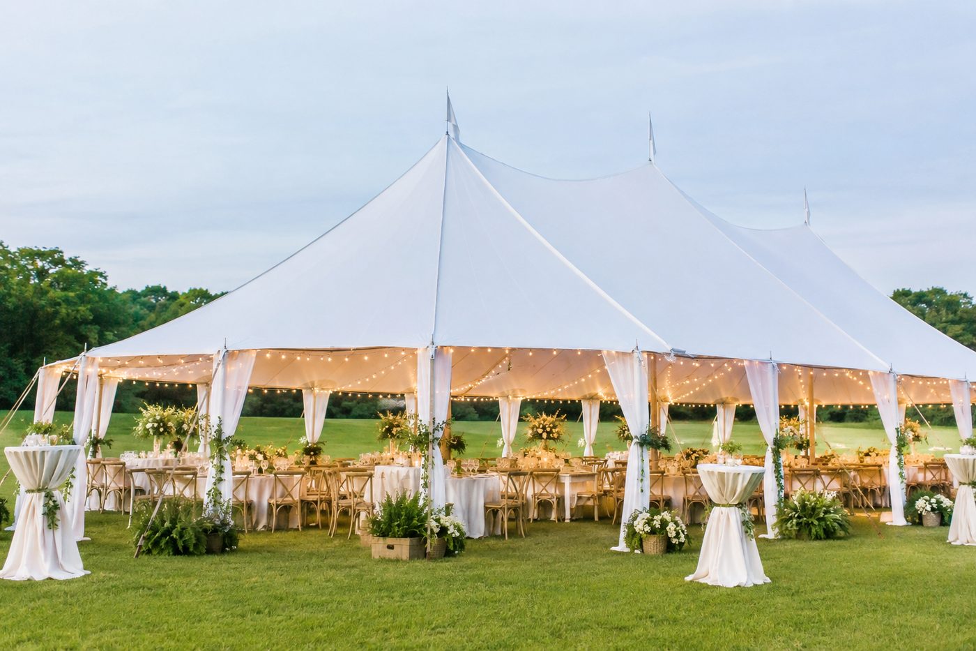 sailcloth tent glowing at dusk over a reception