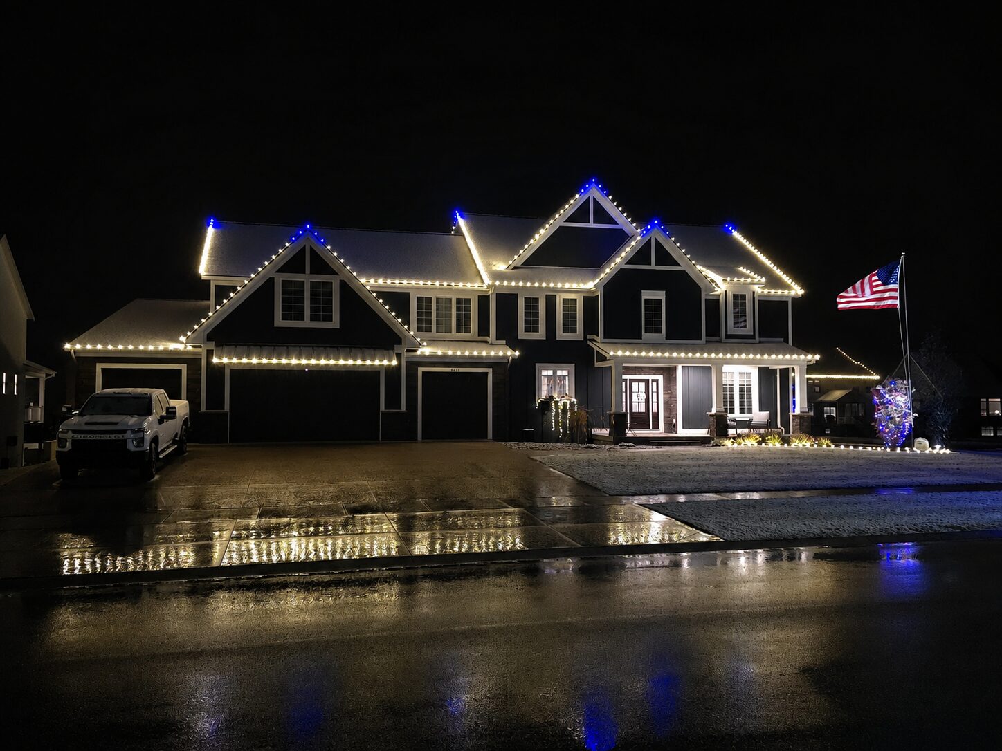 Warm white and blue peak Christmas light installation on a Grand Rapids home