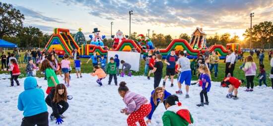 Children enjoying a foam party with colorful inflatable attractions and games at an outdoor event.