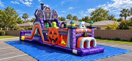 Halloween-themed inflatable obstacle course with pumpkins, ghosts, and a haunted house design set up outdoors.