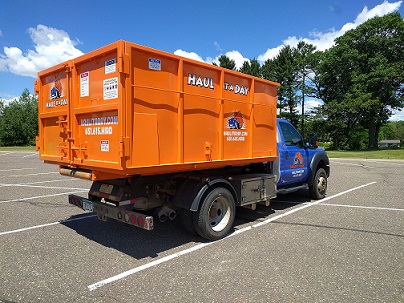 Photo of orange 15 yard roll-off dumpster on blur Haul it a Day truck in parking lot