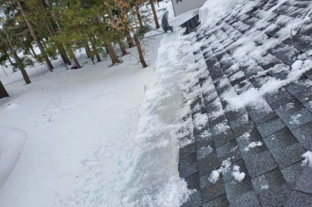 Large ice dam extending across the roofline of a two-story home