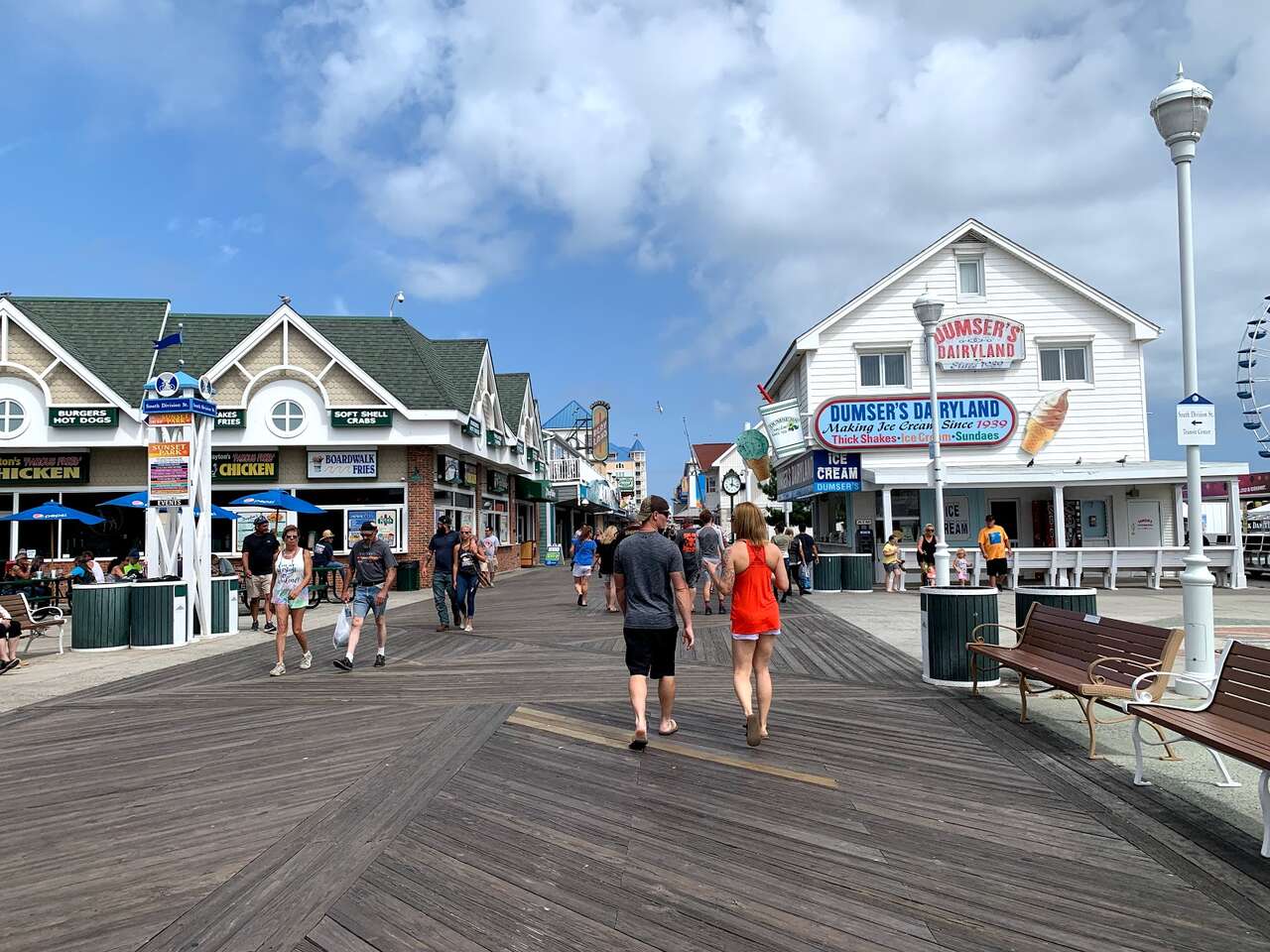 People walking along Ocean City boardwalk past shops and Dumser’s Dairyland.