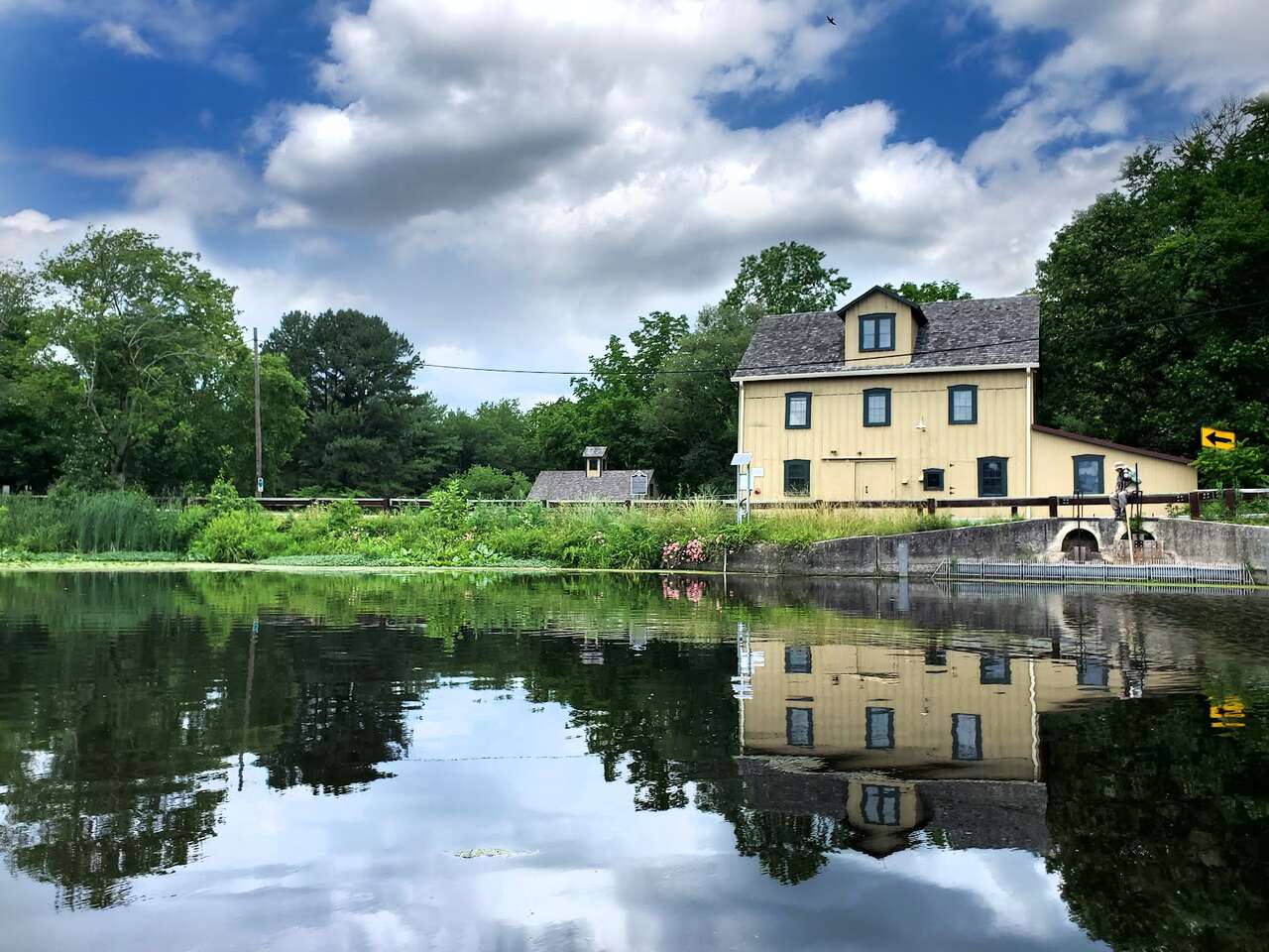 Scenic view of Abbott's Mill reflected in the calm waters of the pond surrounded by lush greenery.