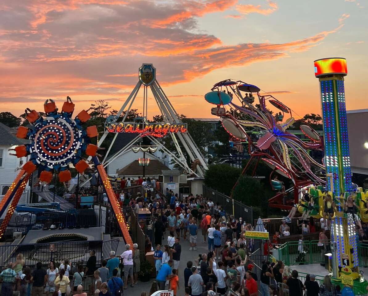 People enjoying carnival rides at sunset.