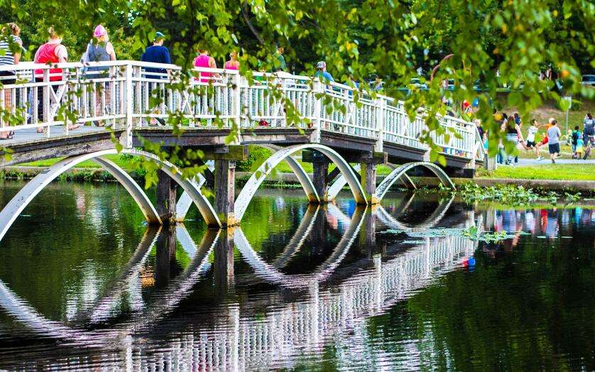 People crossing arched bridge at Mispillion Riverwalk.