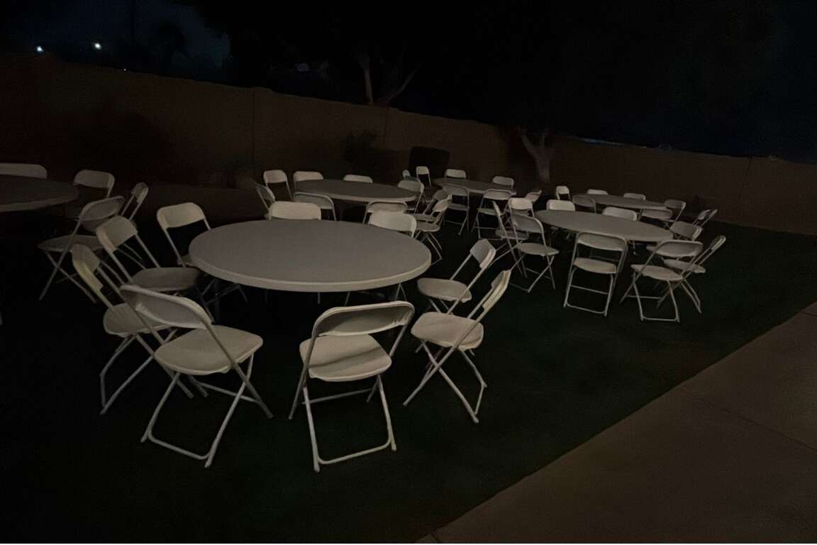 Round table and white folding chair rental setup for a backyard party in Goodyear, AZ