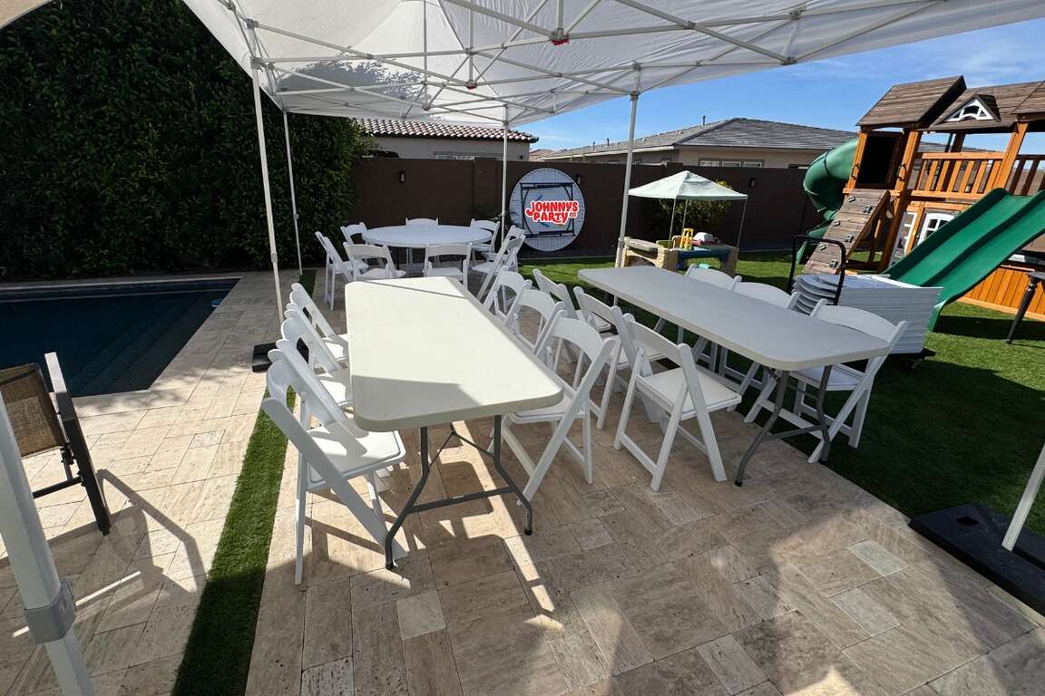 Resin chairs and rectangular tables set up under a canopy