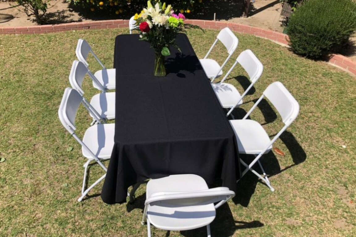 Table and chair rental paired with black linen in backyard setup