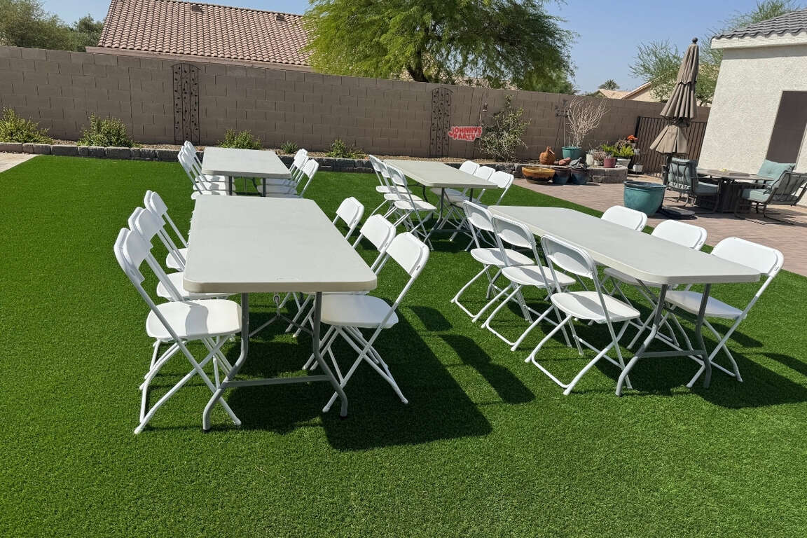 White folding chairs and tables set up on turf lawn in Glendale, AZ