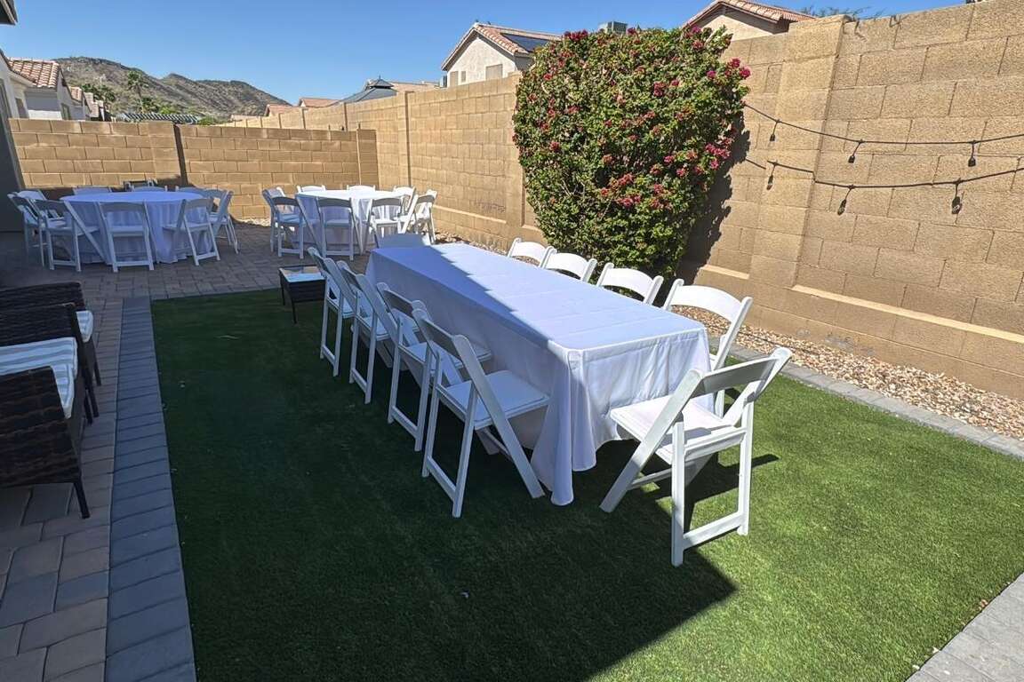 White resin chairs with 60 inch round and 8 ft rectangular tables in a Glendale backyard