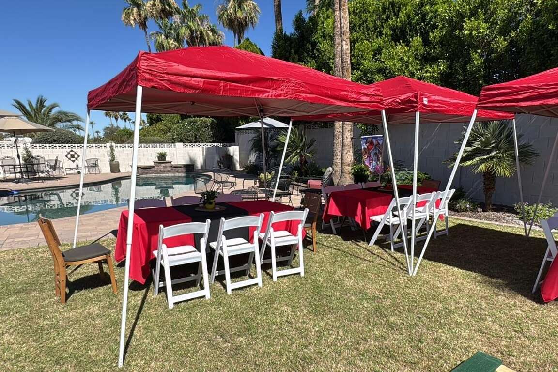 White resin chairs paired with 6ft tables set up under 10x10 canopies