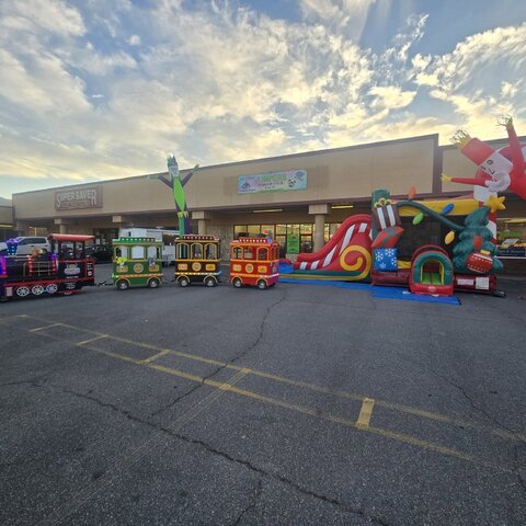 Jumpers trackless train lined up beside a Christmas-themed bounce and slide combo