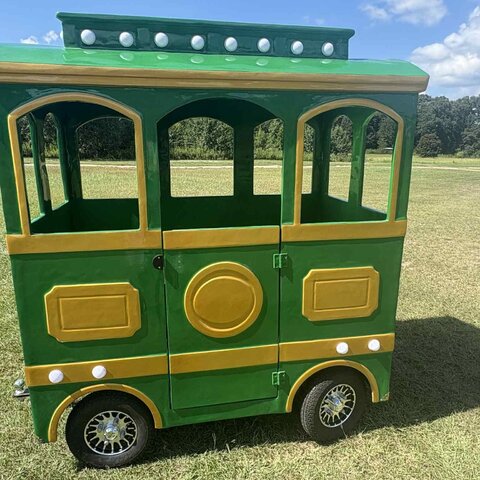 Green and gold trackless train car ready for a holiday event booking in Western NC