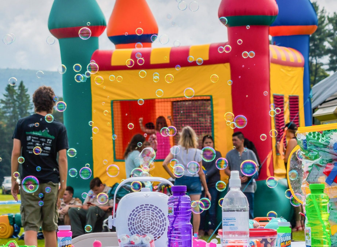 Guests enjoying a party with a bounce house by TUSKany Events Guests enjoying a party with a bounce house by TUSKany Events