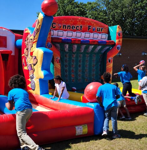 Children playing the Giant Basketball Connect Four inflatable game at an outdoor event near Savannah Georgia