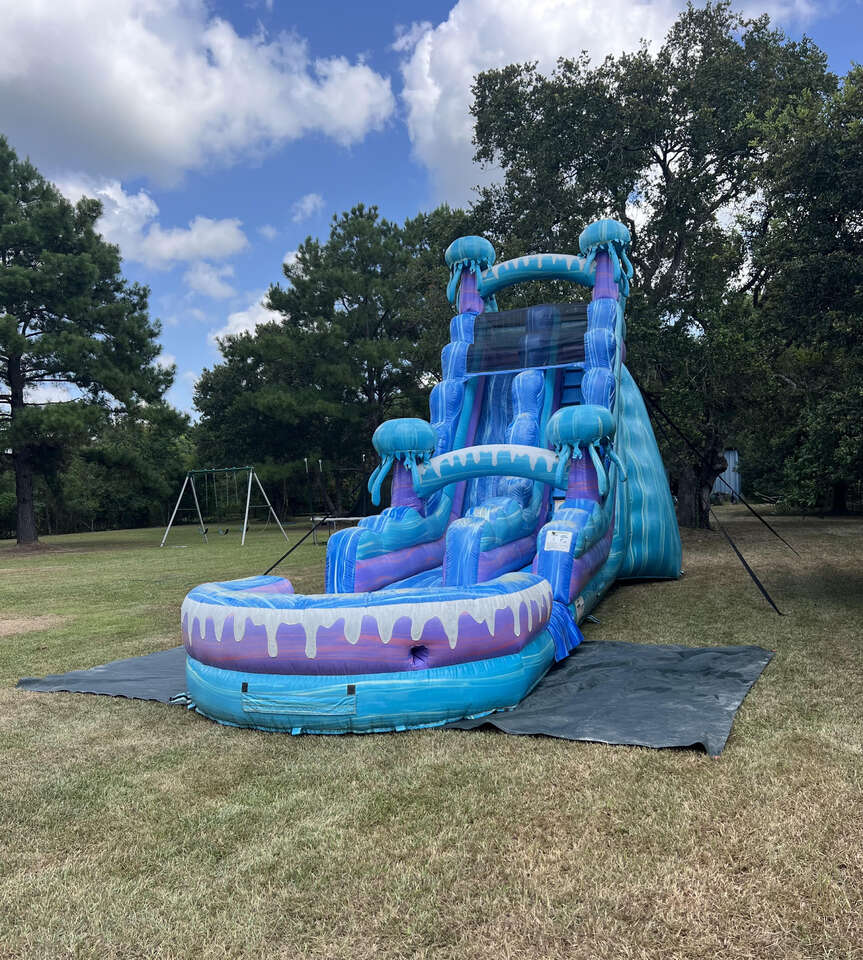 Blue and purple Jump Kings water slide set up on a lawn