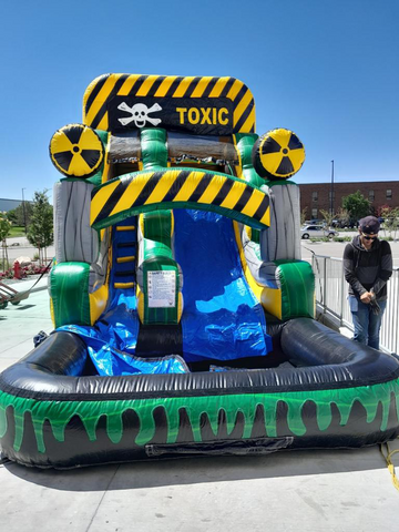 yellow and black atomic water slide sitting on ground on sunny day.