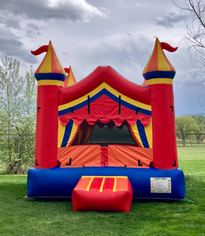 Colorful circus themed bounce house rental on grass for a Childs birthday party.