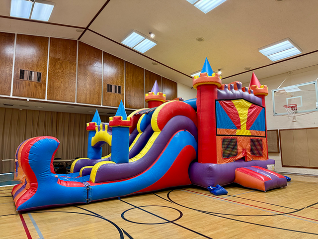 Large colorful bounce house and water slide setup for outdoor event in Utah