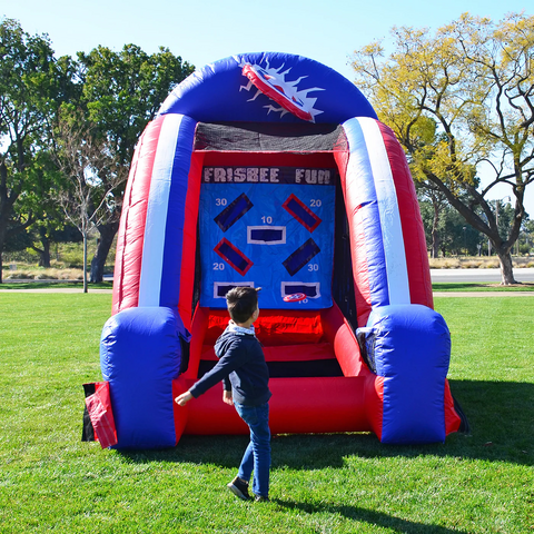 Colorful inflatable frisbee game with young kid playing on it in an open field on a sunny day.