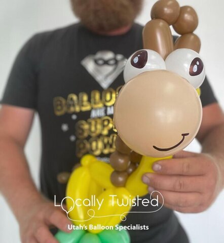 A man holding a brown and yellow animal made out of balloons with a smiley face.