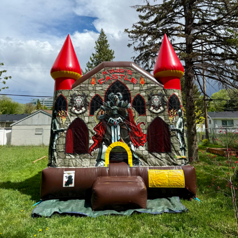 Colorful, medieval themed bounce house set up on grass for a Childs birthday party.