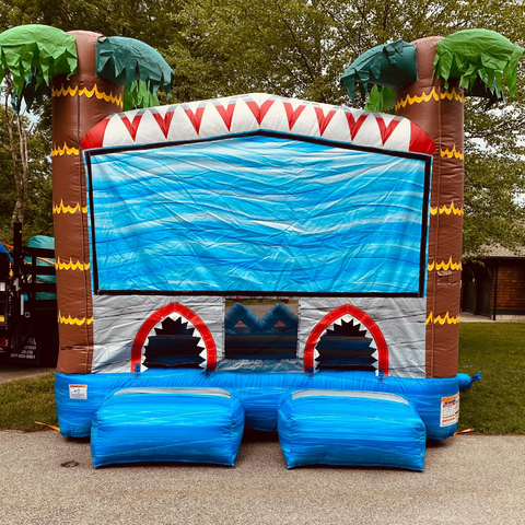 A shark themed bounce house rental in Salt Lake City with green palm trees and a shark tooth design on the top.